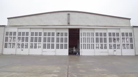 A-man-opens-an-aircraft-hangar-with-propellor-driven-planes-inside