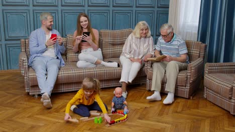 Ocio-Familiar-Multigeneracional-En-Casa-Hablando,-Leyendo-Libros,-Usando-El-Teléfono-Móvil,-Jugando-En-El-Sofá