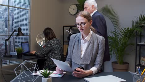 Displeased-upset-young-businesswoman-accountant-reading-documents,-analyzing-financial-papers-data