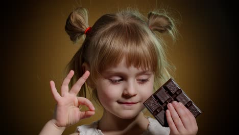 Portrait-of-teen-smiling-child-kid-girl-with-milk-chocolate-bar-showing-thumb-up-gesture,-ok-sign