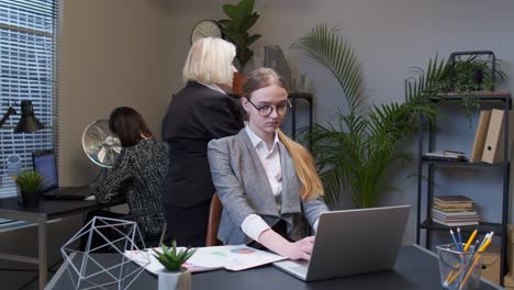 Young-businesswoman-meditates-holds-mind-under-control-practices-yoga-makes-zen-gesture-in-office