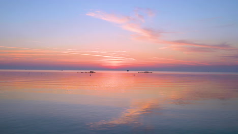 Reflejo-Del-Cielo-De-Nubes-Del-Amanecer-Colorido-Con-Olas-De-Agua-De-Mar-Moviéndose-Con-Viento-Tranquilo-Con-Trampas-De-Pesca-En-El-Fondo-Del-Agua,-Bahréin