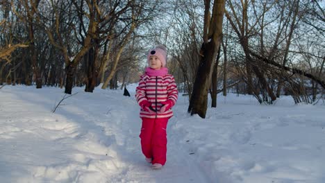 Joyful-child-kid-running,-having-fun,-dancing,-fooling-around-on-snowy-road-in-winter-park-forest