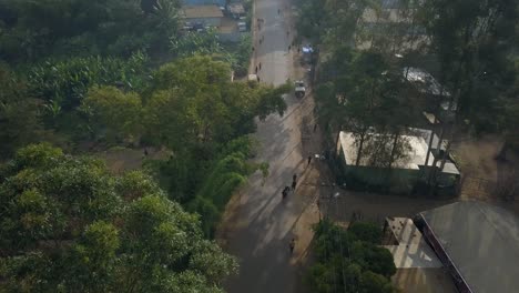 Aerial-view-moving-shot-in-Goroka,-Papua-New-Guinea,-People-walking-on-the-road-car-park-on-the-side,-houses-and-trees-in-the-background