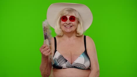 Senior-old-woman-tourist-exhales-from-heat-or-stuffiness,-waves-hand-fan-at-herself-on-chroma-key