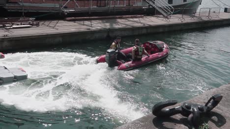 Two-young-Dublin-Fire-Brigade-men,-first-responders,-steering-an-inflatable-rescue-boat-to-leave-the-dock,-slow-motion