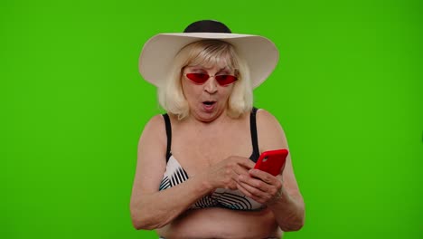 Mature-woman-traveler-browsing-on-mobile-phone-and-celebrating-winning-holiday-resort-vacation