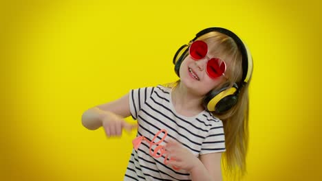 Little-blonde-teen-kid-child-girl-listening-music-via-headphones,-dancing-disco-fooling,-having-fun