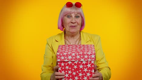 Cheerful-senior-grandmother-woman-opening-gift-box-and-smiling-joyfully,-satisfied-with-nice-present