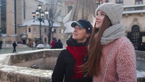 Dos-Mujeres-Sonrientes-Hermanas-Turistas-Caminando-Juntas-Por-Las-Calles-De-La-Ciudad,-Pareja-Hablando,-Abrazándose