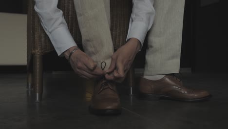 ELEGANT-MAN-DOING-HIS-SHOES-GENTLY,-WEARING-ELEGANT-SHOES-AND-A-WHITE-SHIRT-WITH-A-GREY-PANT