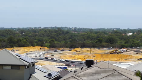 Houses-overlooking-road-construction-site-and-traffic,-forest-in-background,-fixed-wide-shot