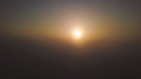 Drone-flies-above-low-lying-clouds-with-nothing-but-a-large-mound-of-rocks-peaking-above-to-capture-the-first-rays-of-sunlight