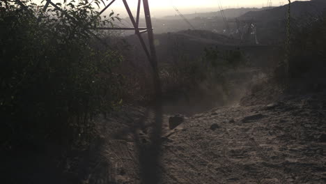 Mountainbiker-Fahren-Bei-Sonnenuntergang-Unter-Stromleitungen-Eine-Felswand-Hinunter-Und-Schwenken-Die-Kamera