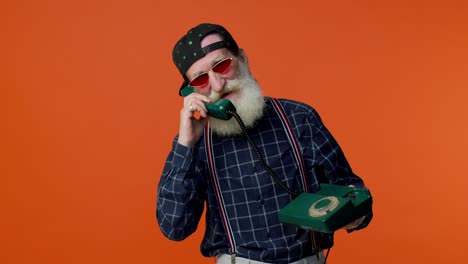 Crazy-elderly-bearded-old-man-talking-on-wired-vintage-telephone-of-80s,-fooling,-making-silly-faces