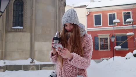 Traveler-woman-with-mobile-phone,-looking-for-route-using-mobile-map-application,-drinking-hot-drink