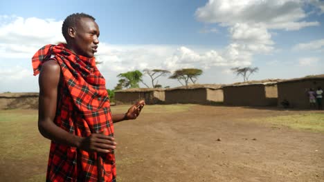 Ein-Massai-Krieger-Zeigt-Das-Dorf-Enkang-Im-Masai-Mara-Nationalpark-In-Kenia