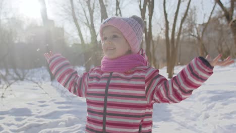 Niña-Alegre-Caminando-Por-Un-Camino-Nevado-En-Un-Parque-Soleado-De-Invierno,-Bosque,-Vacaciones-De-Navidad,-Viajes