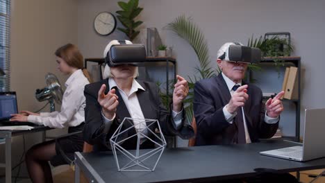 Senior-business-colleagues-using-virtual-reality-3D-app-headset-helmet-doing-research-watching-video