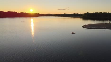 Langsame-Schwenks-Vom-Strand-Zu-Einer-Herrlichen-Goldenen-Stunde,-Während-Kajakfahrer-Vor-Dem-Sonnenuntergang-Davonradeln.-Ich-Bin-Einer-Von-Vielen-Seen-Im-Süden-Der-Twin-Cities-In-Minnesota.