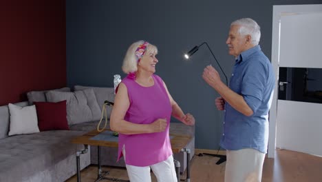 Pareja-Mayor-Bailando-Riéndose-En-Casa.-Abuelos-Relajándose-Divirtiéndose-Celebrando-Aniversario