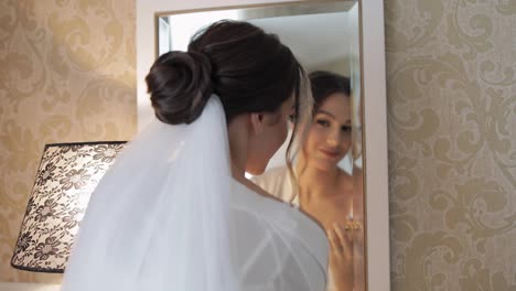 Bride-in-white-boudoir-dress-stay-near-mirror,-looking-at-reflection,-wedding-preparations-at-home