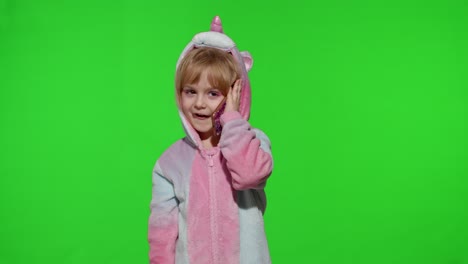 Little-kid-girl-daughter-in-unicorn-pajamas-using-speaking-talking-on-mobile-cell-phone-with-mother