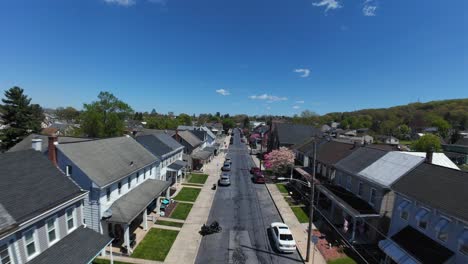 Drone-flight-over-street-with-single-family-homes-in-american-town-at-sunny-spring-day