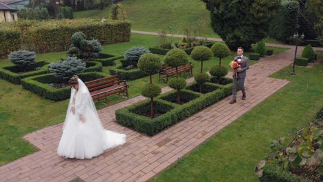 Newlyweds-bride-and-groom-with-bouquet-in-park,-wedding-couple-first-meeting,-aerial-drone-view