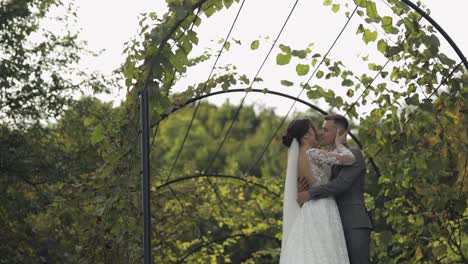 Lovely-newlyweds-caucasian-bride-embracing-groom-in-park-making-kiss,-wedding-couple-family-hugging