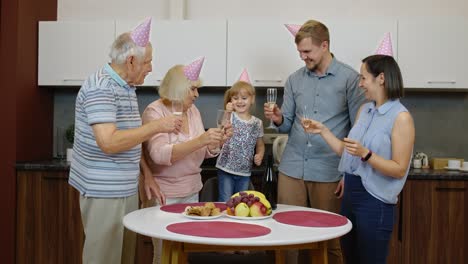 Multigenerational-family-members-with-child-girl-kid-celebrating-birthday-party.-Drinking-champagne