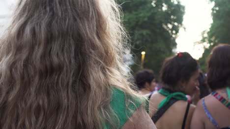 close-up-back-shot-of-female-protestor-near-Cabildo,-two-women-in-green-attire-talk-at-abortion-rally-during-peaceful-protest-for-women's-rights