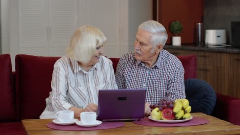 Abuelos-De-Pareja-De-Ancianos-Hablando-Y-Usando-Una-Computadora-Portátil-Digital-En-Casa.-Compras-Por-Internet