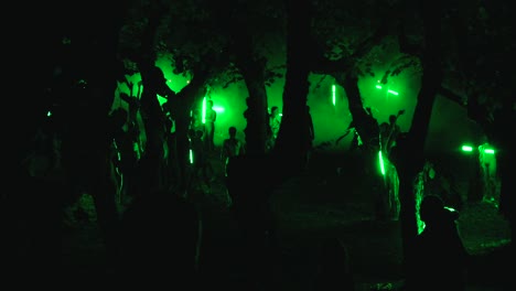 Un-Grupo-De-Bailarines-Realizando-Danzas-étnicas-En-La-Oscuridad,-Rodeados-De-árboles.