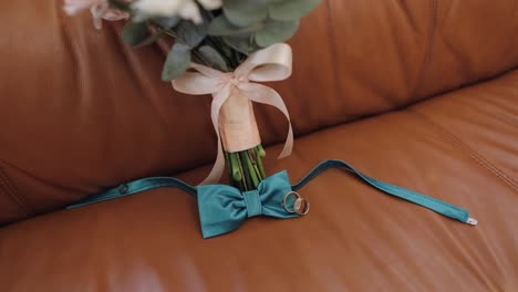 Beautiful-wedding-bouquets-lie-with-wedding-rings-and-grooms-bow-tie-on-sofa