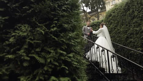 Newlyweds,-caucasian-groom-with-bride-stay-on-stairs-in-park,-wedding-couple,-man-and-woman-in-love