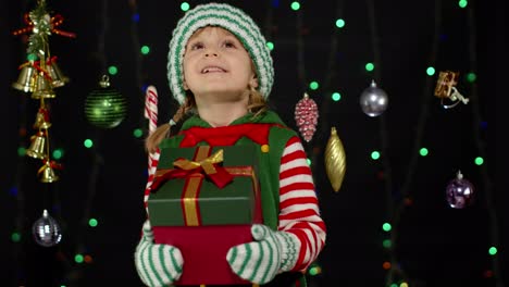 Kid-girl-Christmas-elf-Santa-helper-giving-present-gift-box-to-camera.-Happy-New-Year-holidays