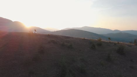 Newlyweds-stand-on-a-high-slope-of-the-mountain.-Groom-and-bride.-Aerial-view