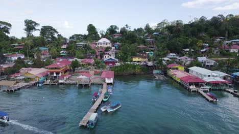 Aerial-view-of-a-colorful-village-on-stilts,-showing-boats-navigating-the-turquoise-waters-of-bastimentos-island