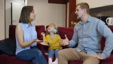 Child-girl-trying-to-be-distracted-and-not-hear-quarrels-between-parents-at-home.-Family-problems