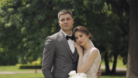 Newlyweds,-caucasian-groom-with-bride-walking,-embracing,-hugs-in-park,-wedding-couple