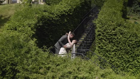 Newlyweds,-caucasian-groom-with-bride-stay-on-stairs-in-park,-wedding-couple,-man-and-woman-in-love