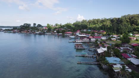 Vista-Aérea-De-La-Pintoresca-Costa-De-La-Isla-De-Bastimentos-En-Panamá,-Con-Casas-Vibrantes-Y-Exuberante-Vegetación-Junto-Al-Agua.