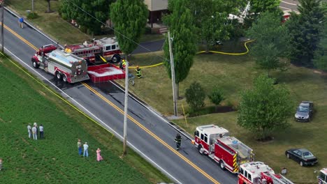 Aerial-tracking-shot-of-many-firetrucks-on-rural-street-during-firefighting-operations-in-USA