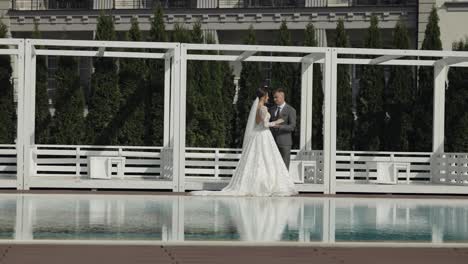 Newlyweds-caucasian-bride-groom-walking-near-swimming-pool,-holding-hands,-wedding-couple-family