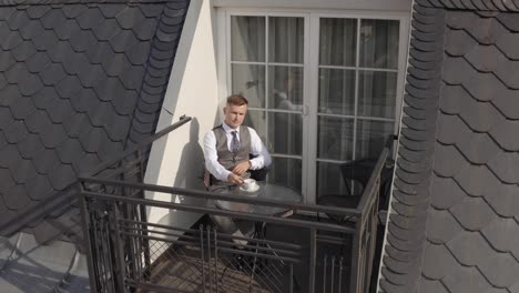 Man-groom-businessman-is-drinking-coffee-from-a-white-cup-on-the-balcony-at-home-in-wedding-morning