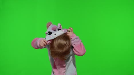 Little-blonde-child-girl-smiling,-putting-on-unicorn-costume-pajamas-on-chroma-key,-slow-motion