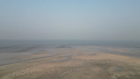 Vista-Aérea-De-Olas-Relajantes-Y-Suaves-Que-Fluyen-Hacia-Una-Playa-En-Un-Día-Nublado-Y-Sombrío-Palghar-Maharashtra-India-4k