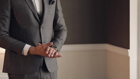 Handsome-stylish-groom-man-looking-on-wrist-watch-at-home-gets-ready-before-date,-meeting-with-bride