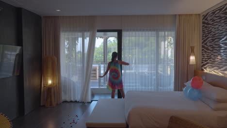 Frau-Im-Kleid-öffnet-Den-Vorhang-Eines-Hotelzimmers-Im-Renaissance-Bali-Uluwatu-Resort-And-Spa,-Bali,-Indonesien